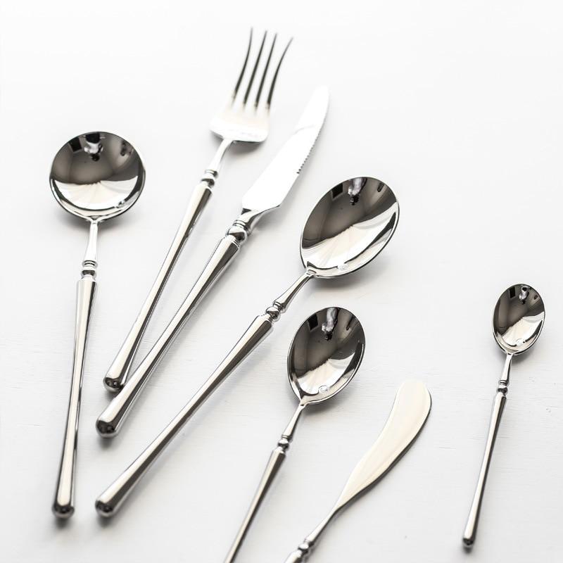 Set of silver cutlery including spoons and a fork on a white background