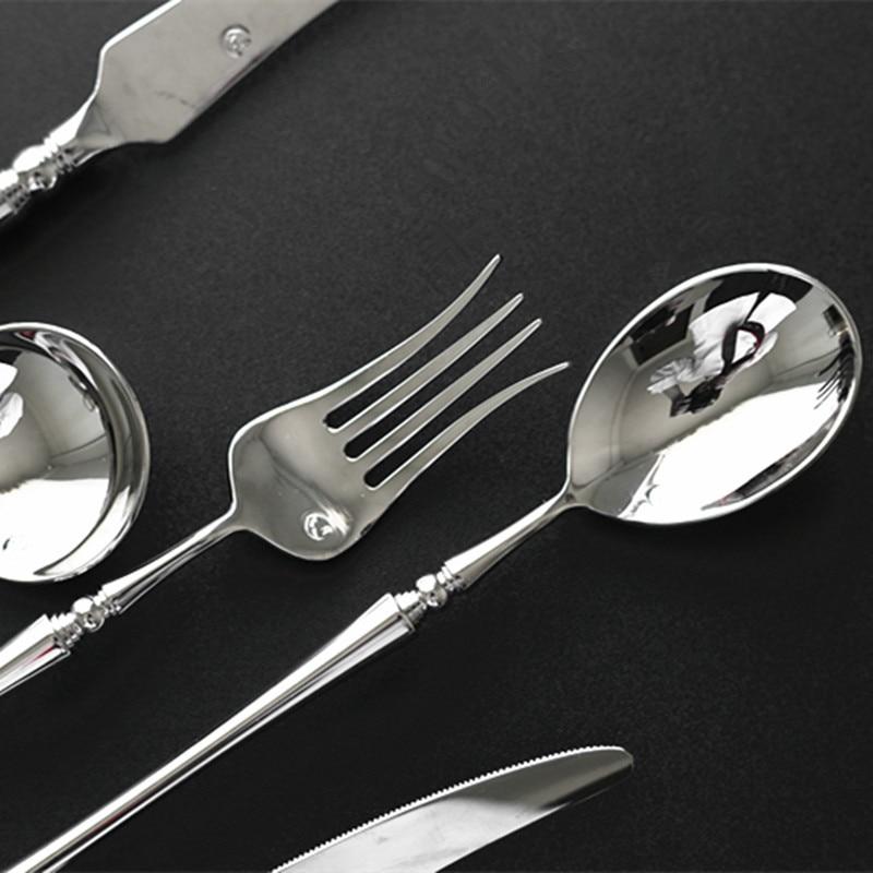 Silver cutlery set including fork, spoon, and knife on a black background