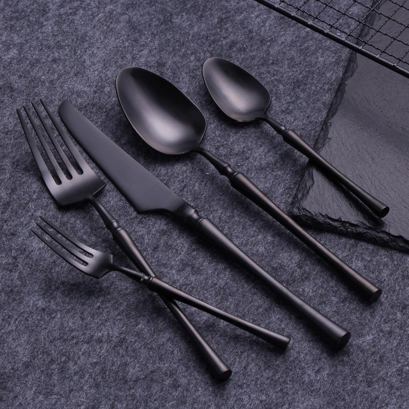Set of black cutlery including fork, knife, and spoons on a dark surface.