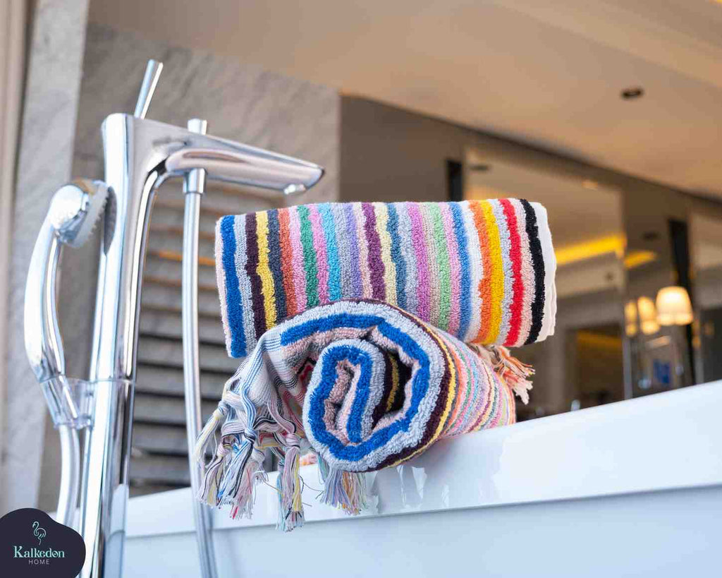 Folded rainbow striped hand towel with fringes on bathtub edge in modern bathroom