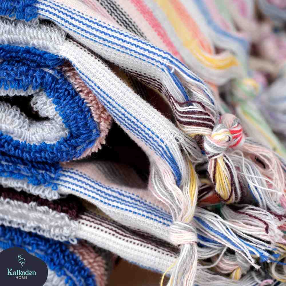 Close-up of rainbow striped hand towel with colorful fringed edges and woven texture.