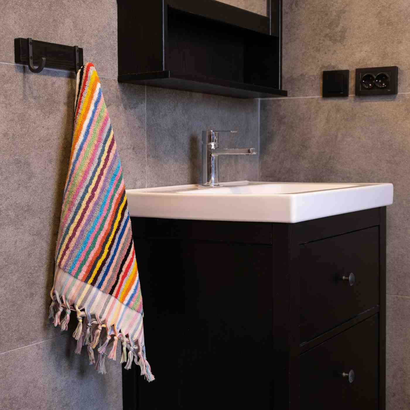 Rainbow striped hand towel with tassels hanging by a modern bathroom sink