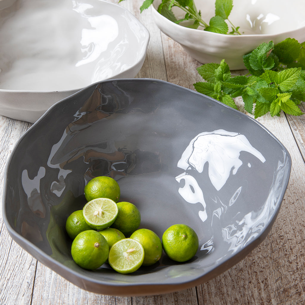 Gray ceramic bowl with limes on a wooden surface