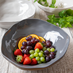 Gray bowl filled with fruits on a wooden surface