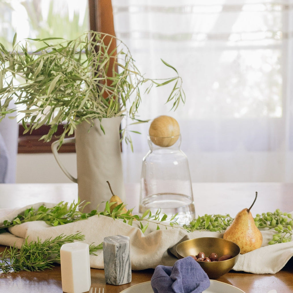 Table setting with pears, plants, and decorative items on a wooden surface.