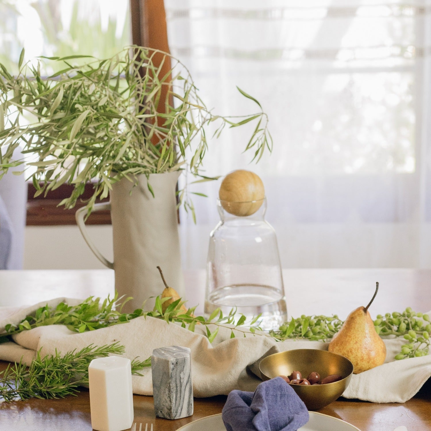 Table setting with pears, plants, and decorative items on a wooden surface.