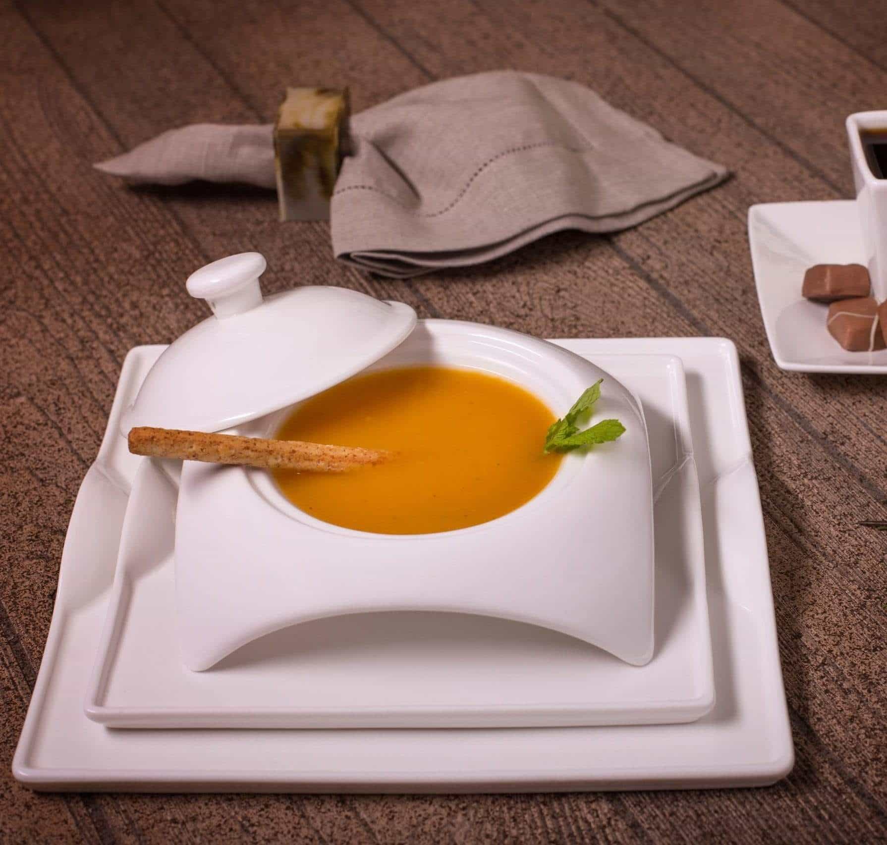 Modern white square dinnerware set with soup bowl and breadstick on rustic table