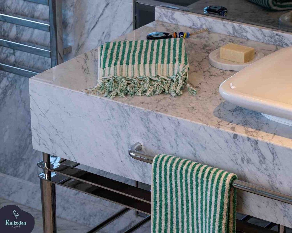 Green striped jacquard hand towel with fringes on marble bathroom sink