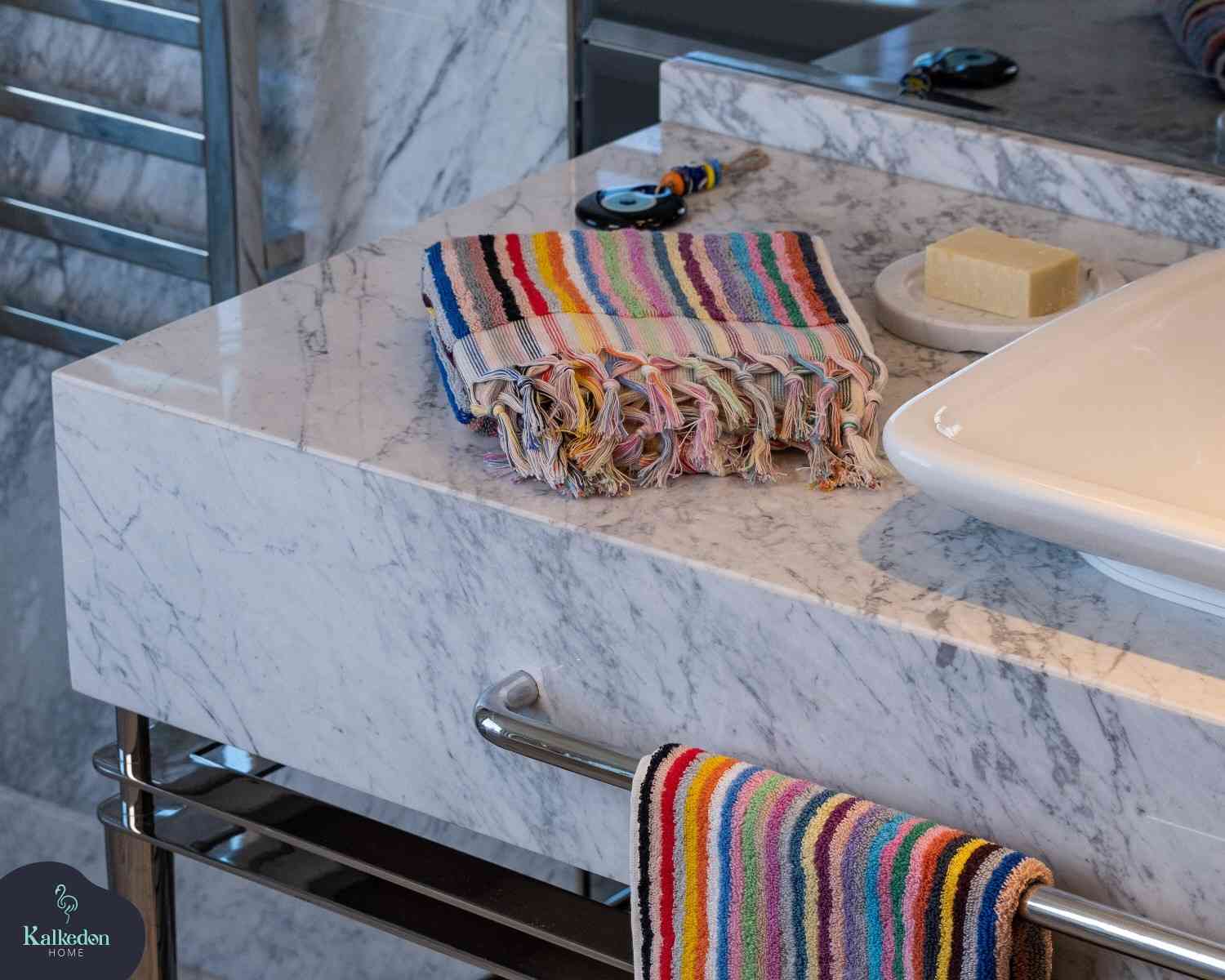 Striped jacquard rainbow hand towel with fringe on marble bathroom countertop