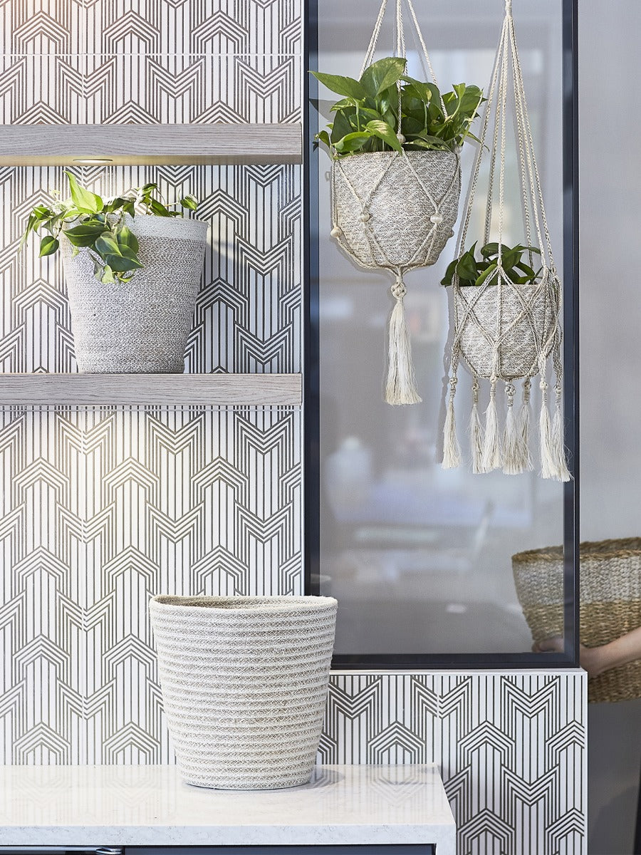 Room with geometric patterned wallpaper, plants, and a macrame plant hanger.