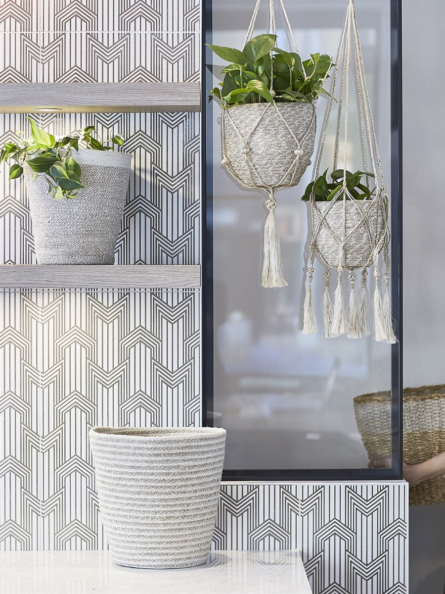 Hanging planters with geometric wallpaper and a mirror in the background