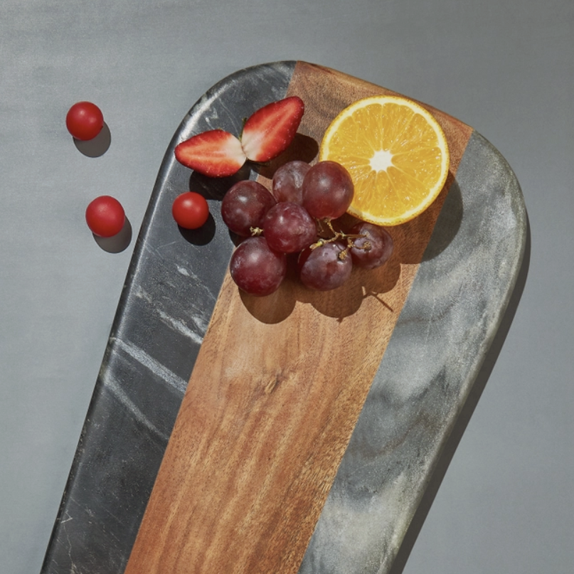 Wooden and stone cutting board with fruits on a gray background