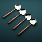 Four spoons with copper handles and metal bowls on a dark green background