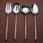 Set of four silver cutlery items with copper handles on a brown background