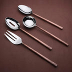 Set of four silver utensils with copper handles on a brown background