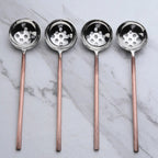 Four ladles with copper handles on a marble background