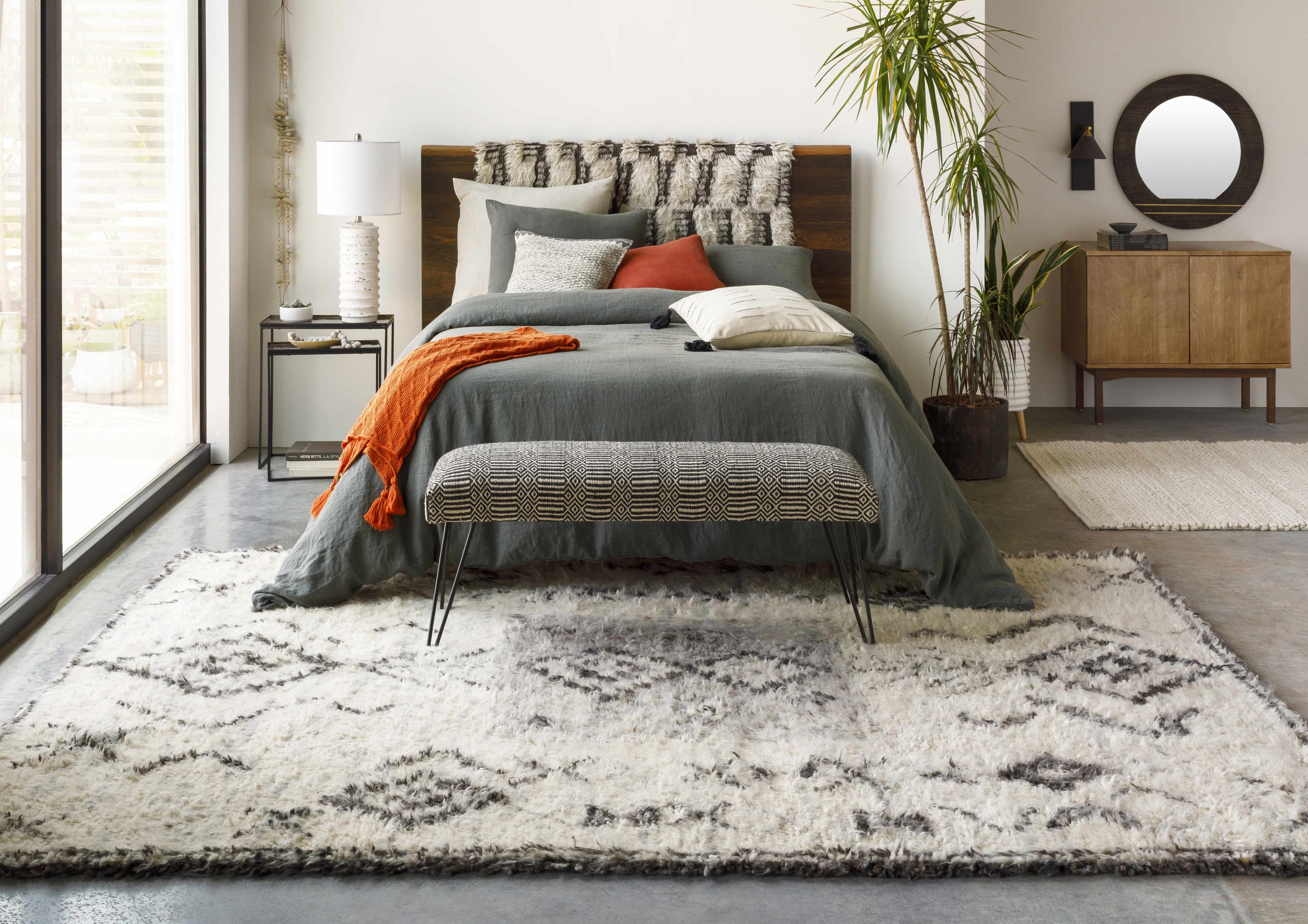 Modern bedroom with a bed, bench, and decorative items.