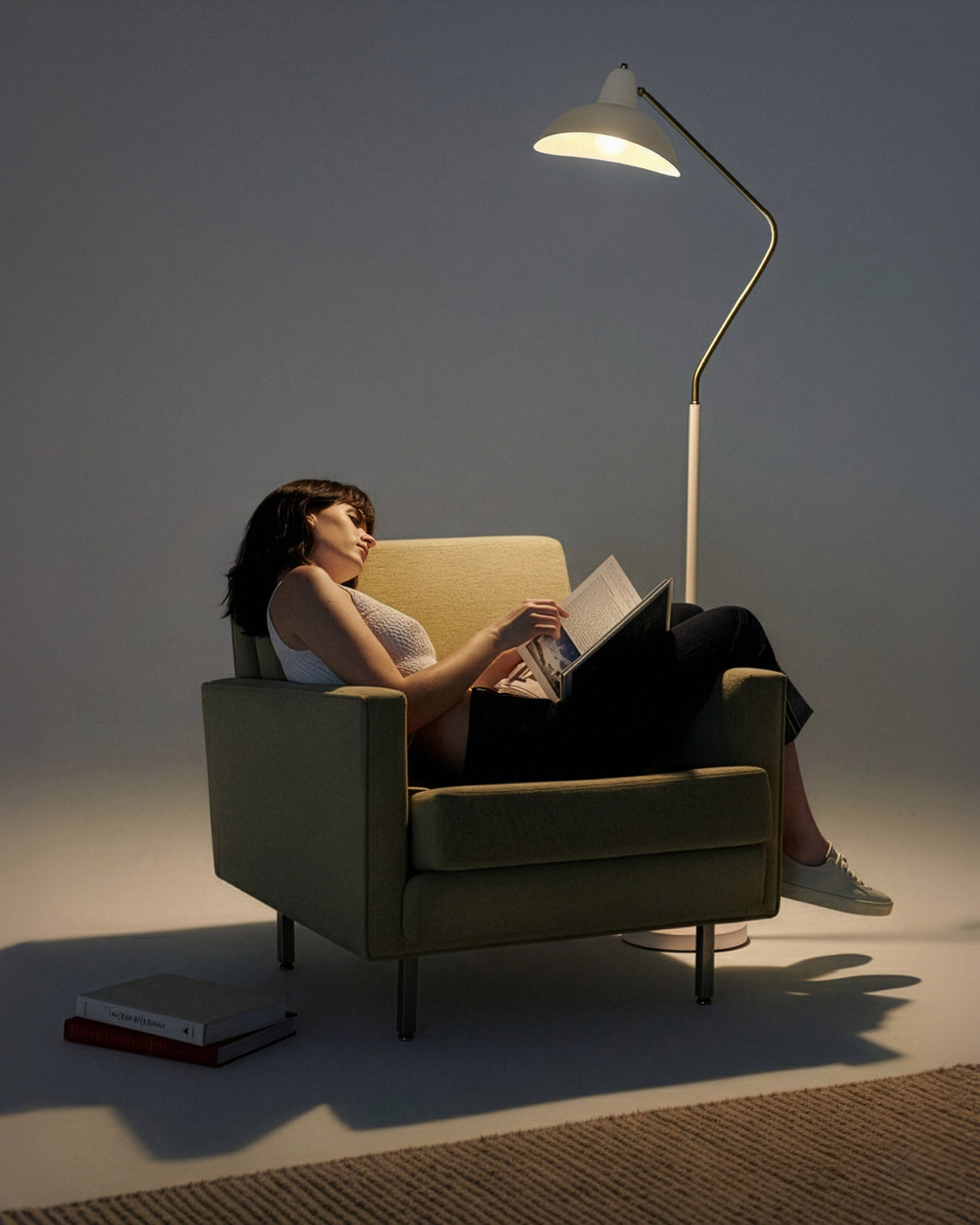 Woman reading a book in a dimly lit room with a floor lamp.