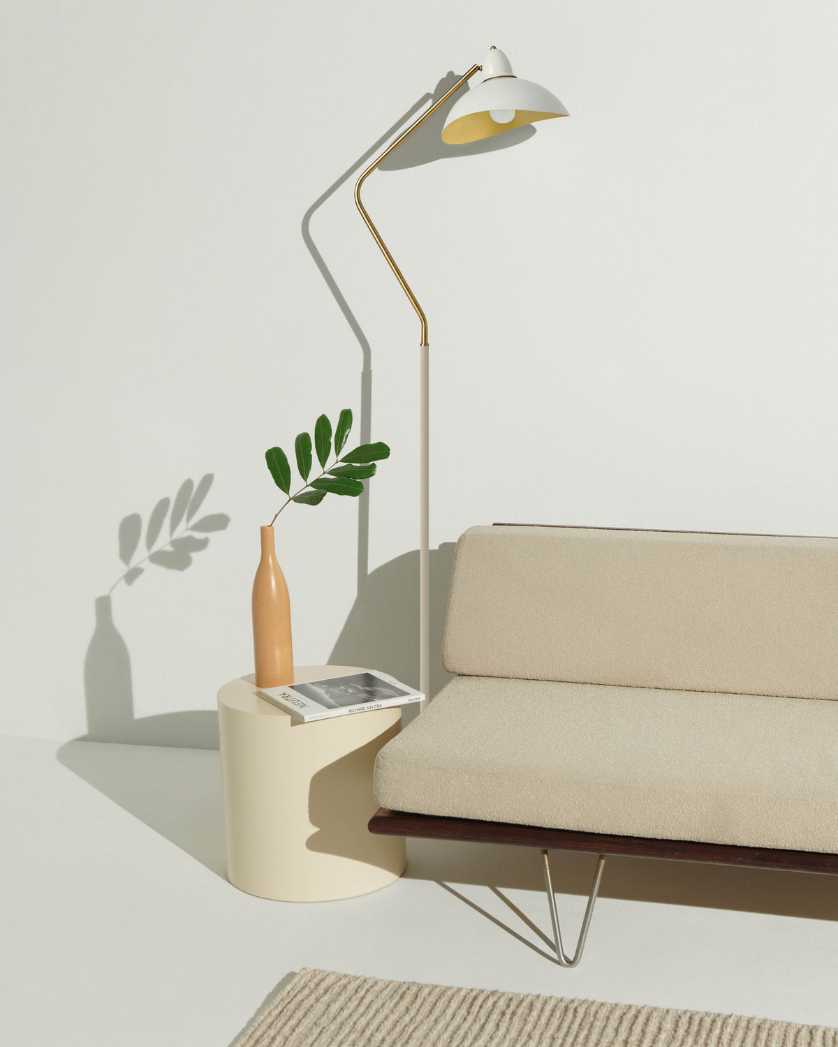 Modern living room with a beige sofa, floor lamp, side table, and plant.