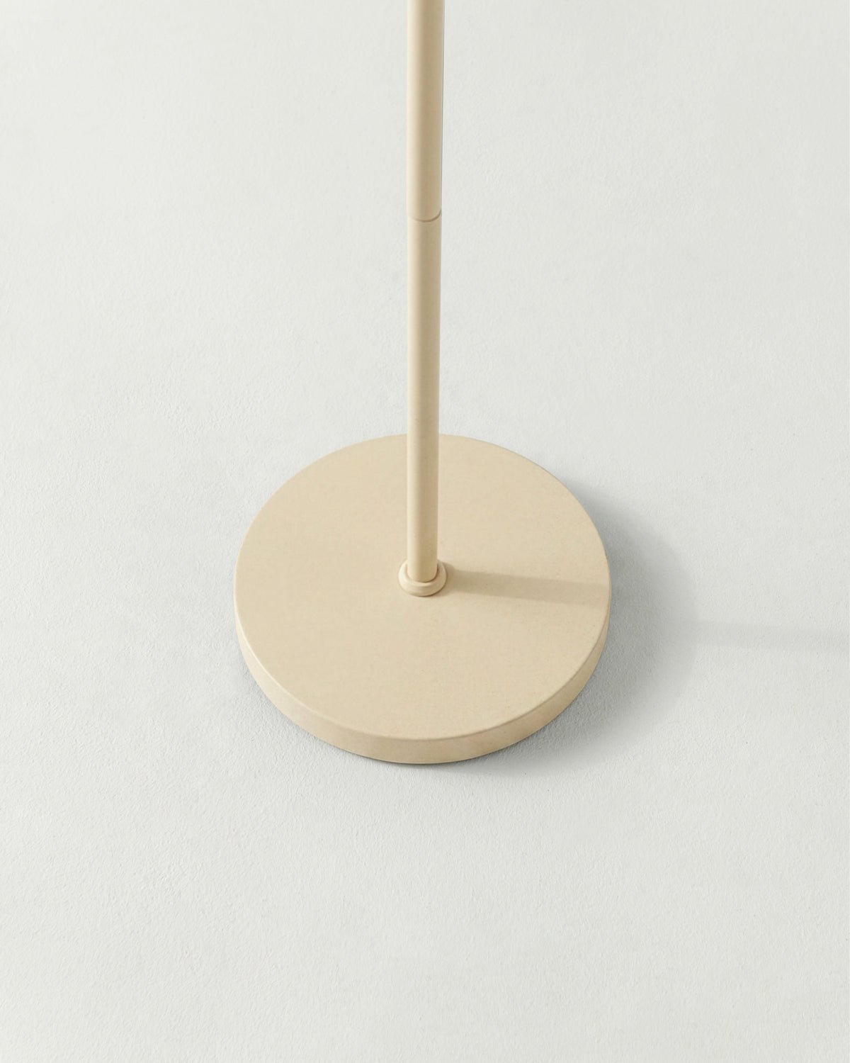 Beige floor lamp with a round base on a light gray background