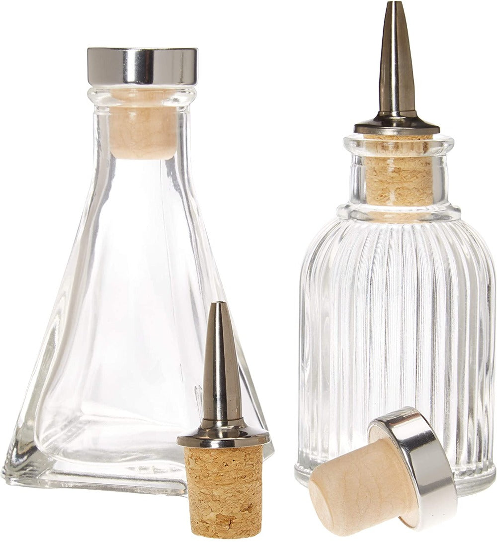 Two glass condiment bottles with metal nozzles and cork tops on a white background