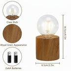 Wooden table lamp with clear bulb, wood grain appearance, and 2AA batteries on a white background.