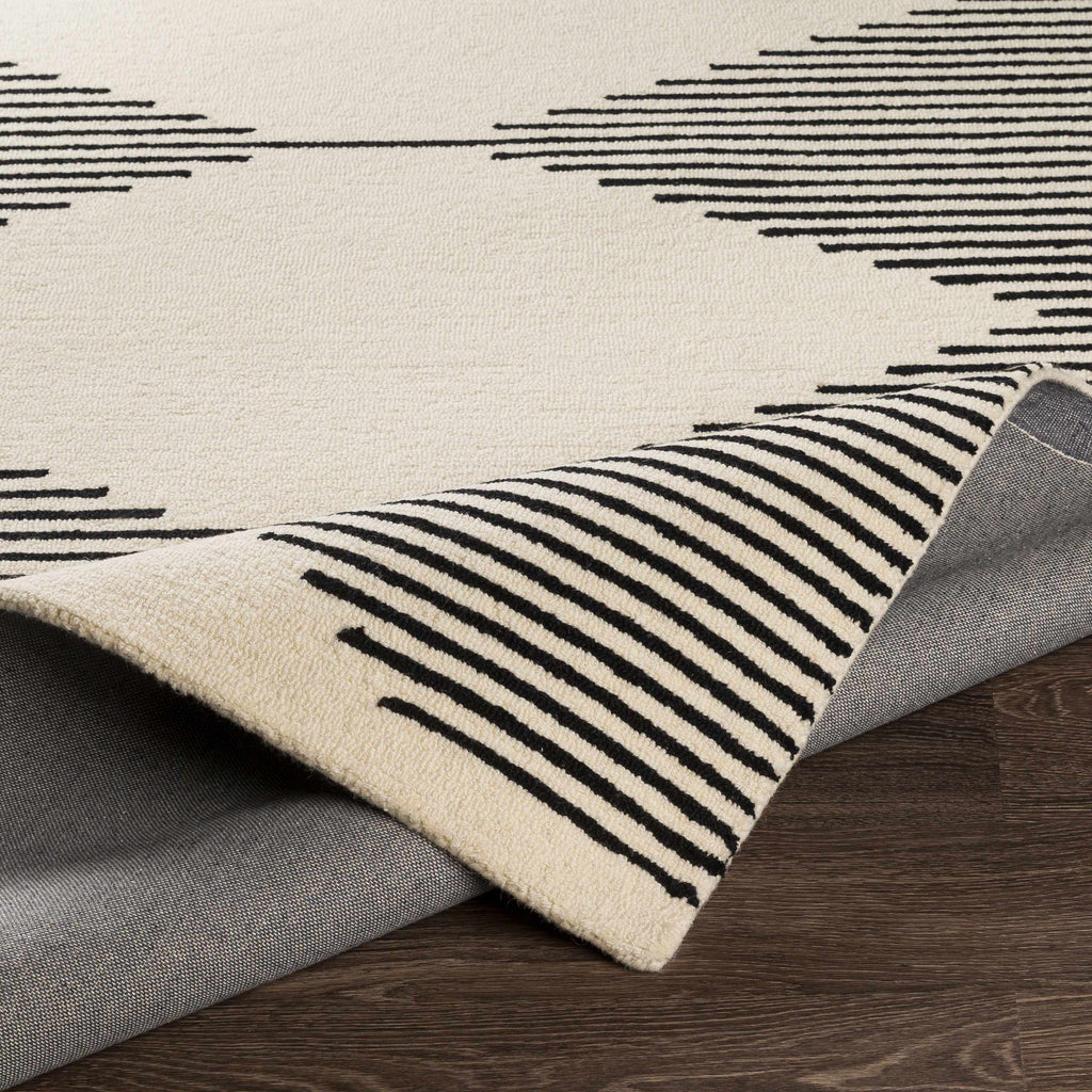 Close-up of a rug with black geometric patterns on a wooden floor