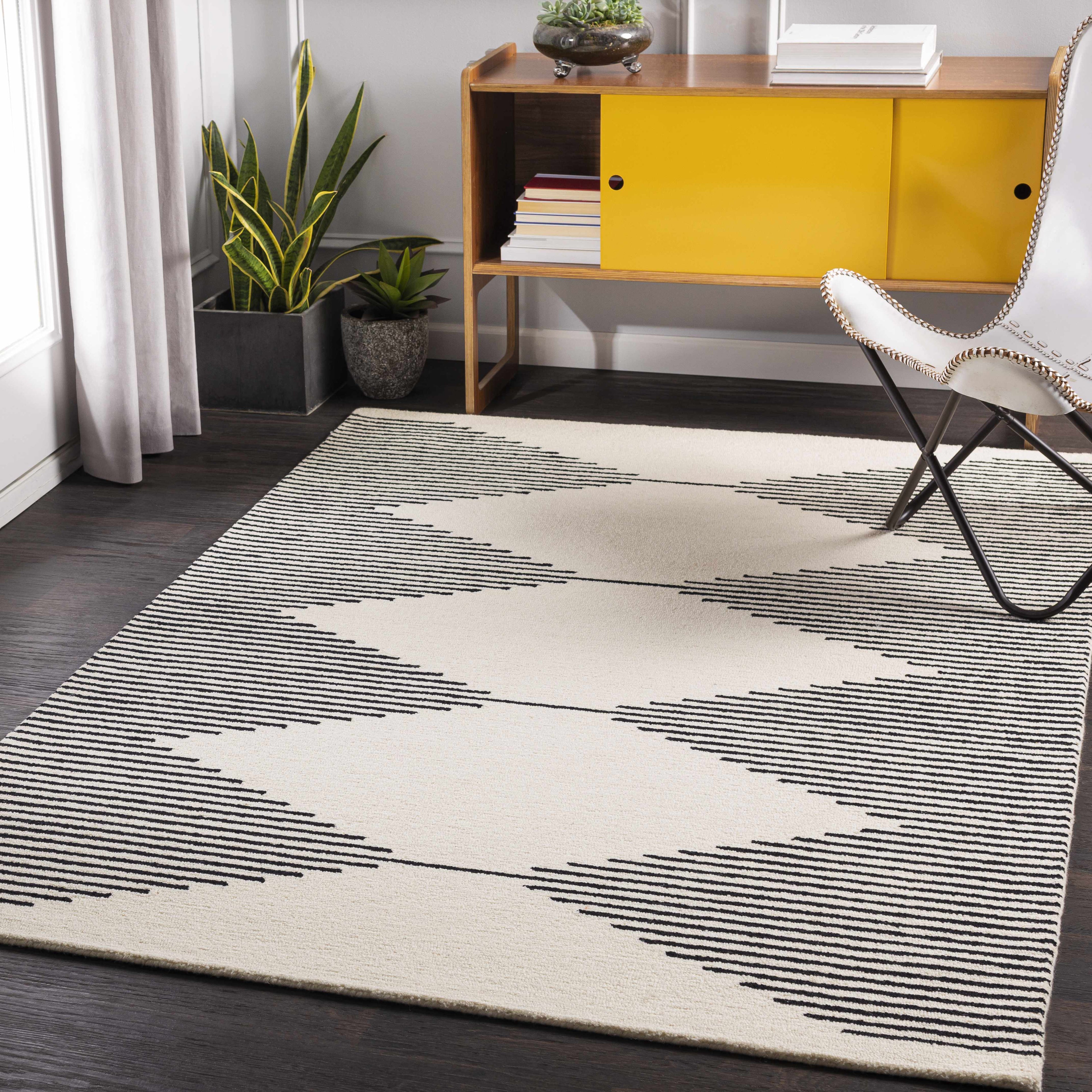 Modern room with a patterned rug, chair, and yellow cabinet.
