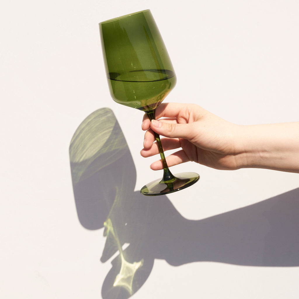 Hand holding a green wine glass against a white background