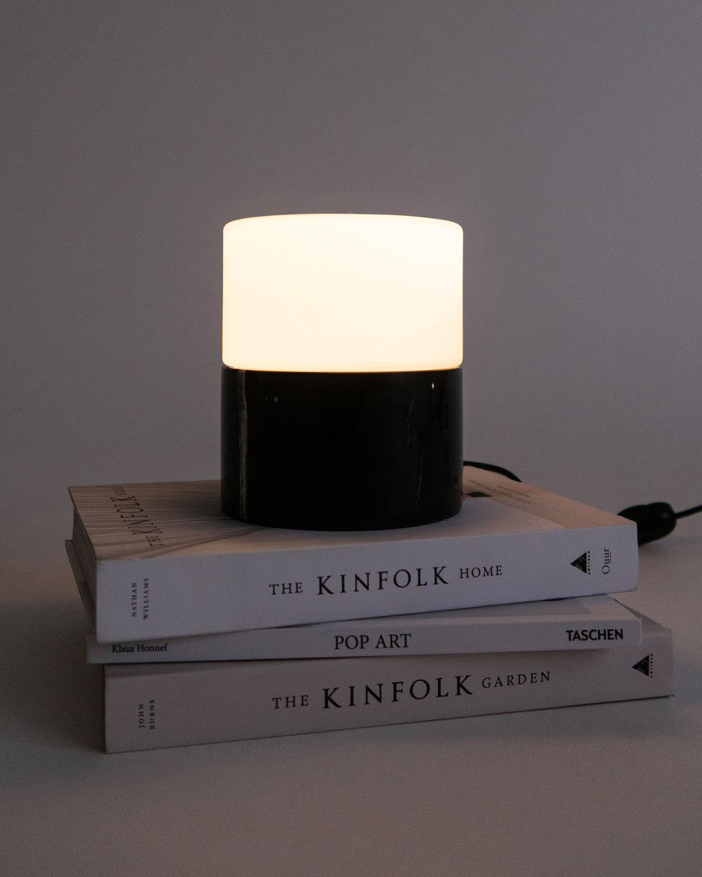 Black and white cylindrical lamp on a stack of books with a gray background